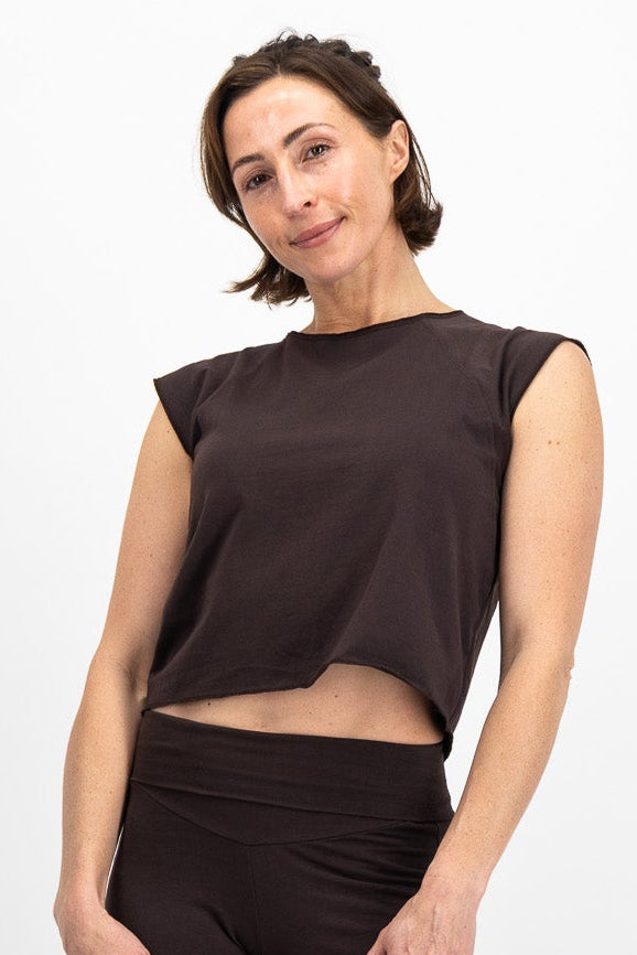Woman wearing a brown top and flared pants on a white background