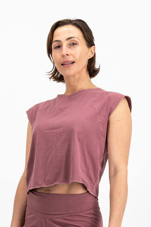 Woman wearing a mauve sleeveless top and shorts on a white background